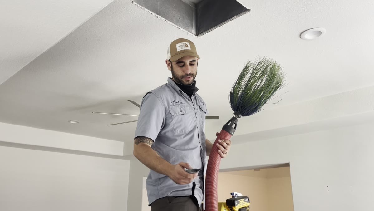 A technician holding a rotary brush used for deep duct cleaning